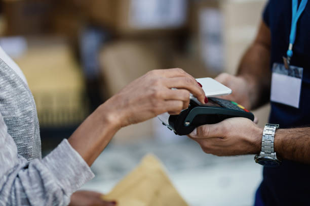 istock Close-up of female customer using smart phone while paying to delivery man. 1186583195