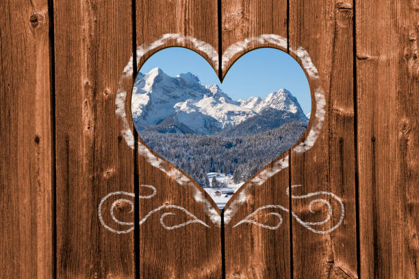 Looking through a carved heart in a wooden wall to beautiful snow covered landscape