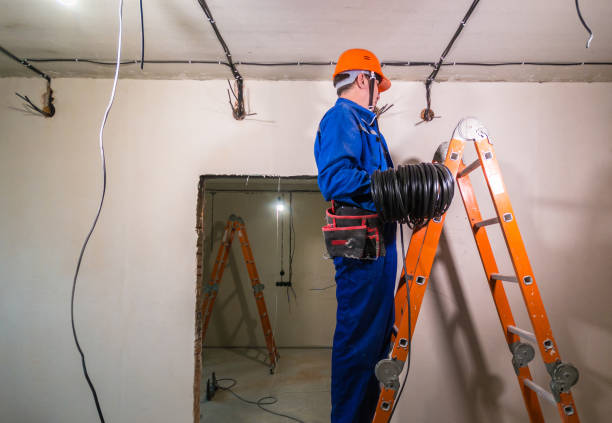 istock Electrician in hard hat and uniform holding a cable roll in his hands 1186589642