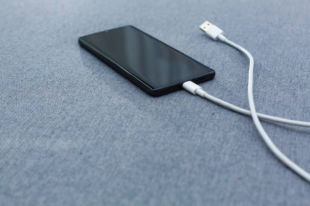 istock Mobile smart phones charging on gray background 1186590599