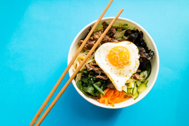 Bibimbap with beef, egg and vegetables on blue baclground. Korean cuisine. Top view.