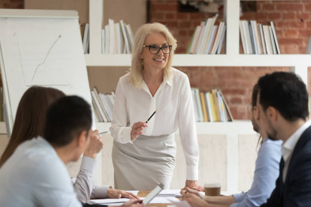 middle age company boss and employees interact during briefing - leadership business women senior adult imagens e fotografias de stock