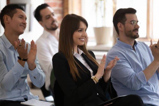 istock Diverse businesspeople sit in row applauding accomplishing seminar 1186603949