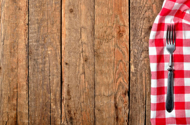 istock Fork on red checkered tablecloth right frame on vintage wooden table background - view from above 1186604046