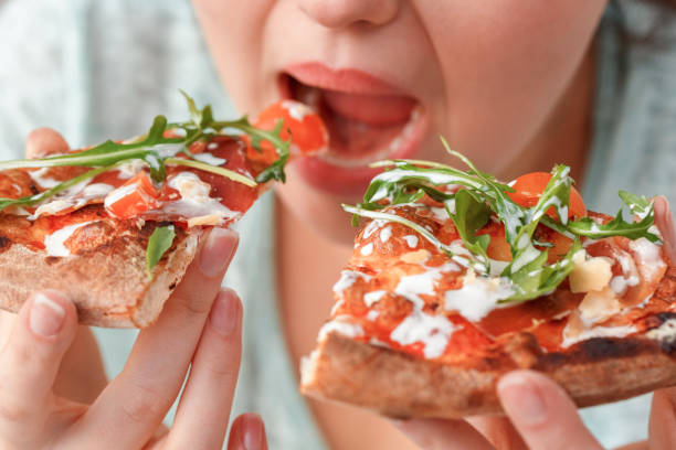 istock Binge Eating. Chubby girl sitting at kitchen table eating pizza fast close-up 1186604363