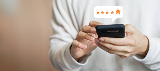 close up on customer man hand pressing on smartphone screen with gold five star rating feedback icon and press level excellent rank for giving best score point to review the service , technology business concept close up on customer man hand pressing on smartphone screen with gold five star rating feedback icon and press level excellent rank for giving best score point to review the service , technology business concept customer focused stock pictures, royalty-free photos & images