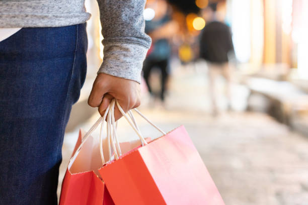 close up man hand holding red shopping bag while walking at outside city street for sale promotion in boxing day ,christmas festival ,winter fashion collection and happy new year concept cerca de la mano del hombre sosteniendo la bolsa roja de la compra mientras camina en la calle de la ciudad fuera para la promoción de la venta en el día del boxeo, festival de navidad, colección de moda de invierno y concepto feliz de año nuevo