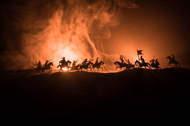 istock Medieval battle scene with cavalry and infantry. Silhouettes of figures as separate objects, fight between warriors on dark toned foggy background. Night scene. 1186610666