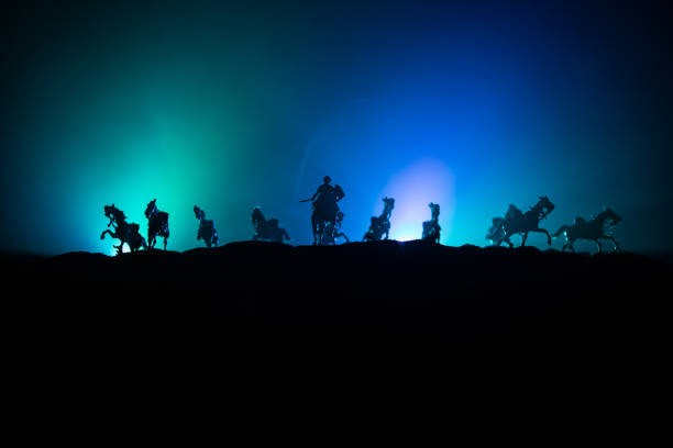 istock Medieval battle scene with cavalry and infantry. Silhouettes of figures as separate objects, fight between warriors on dark toned foggy background. Night scene. 1186610667