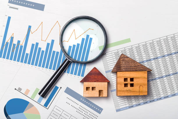 Magnifying glass, mini wooden house and papers with data