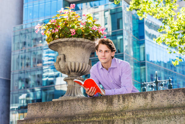 istock Young Man reading book, thinking, relaxing outside in New York, 1186620429
