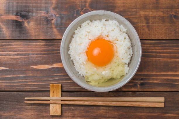 un huevo crudo sobre arroz y palillos - chopsticks rest kitchen utensil dishware horizontal fotografías e imágenes de stock