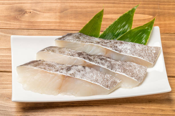 филе трески на древесном зерновом фоне - cod fillet raw prepared fish стоковые фото и изображения