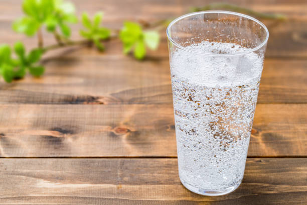 kohlensäurehaltiges wasser auf holzkornhintergrund - soda stock-fotos und bilder