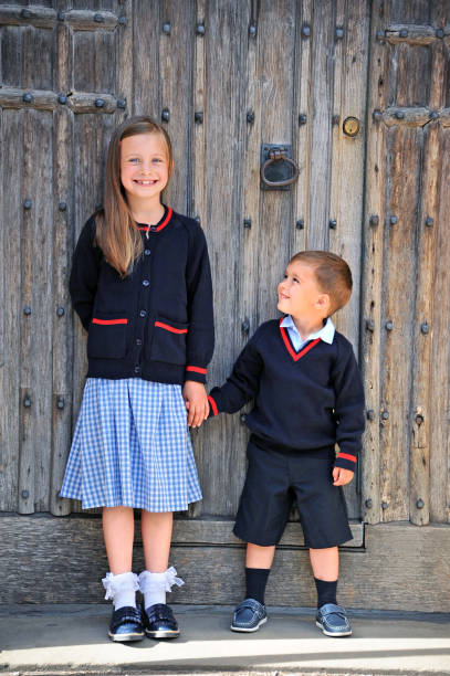 Portrait of School Children Outside Primary school aged siblings all ready for their first day at school. The young girl's brother is excited that he finally gets to join his big sister at private school this year. cambridge england photos stock pictures, royalty-free photos & images