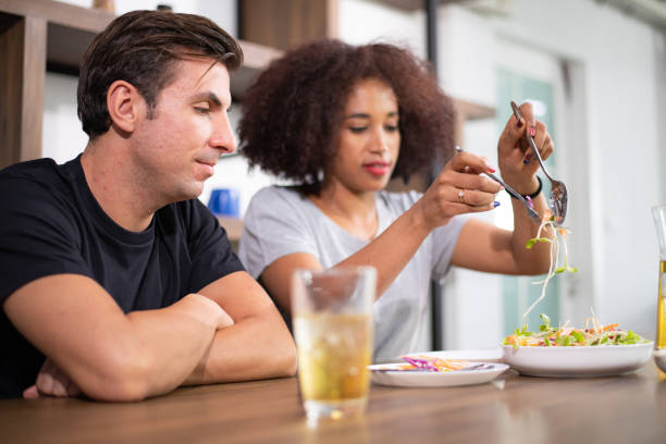 istock Young couple is feeding each other and smiling while cooking salad and hamburger in kitchen 1186640064