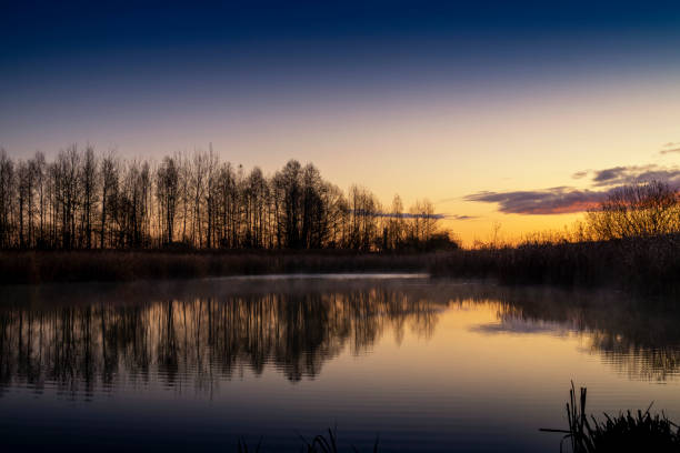 istock Vivid orange sunset reflected in a tranquil lake 1186641730