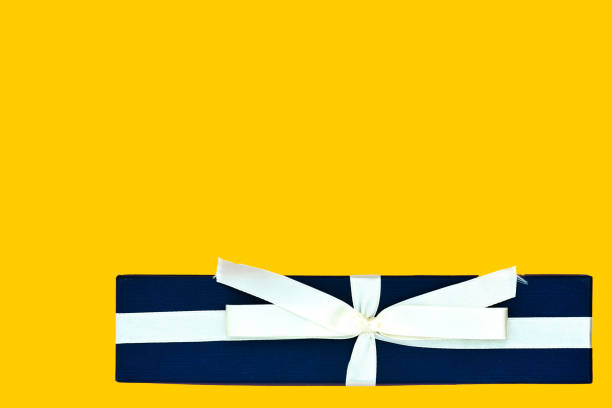 istock Blue gift box with a beige ribbon on a bright yellow background. Top view, copy space 1186646812