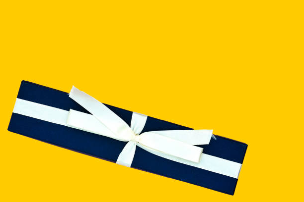 istock Blue gift box with a beige ribbon on a bright yellow background. Top view, copy space 1186646814