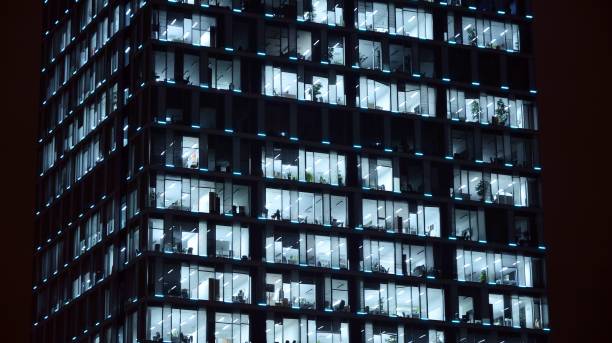 istock Pattern of office buildings windows illuminated at night. 1186646953