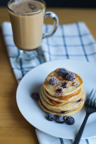 istock fritter or pancakes with blackberry, frozen berries, fork on plate and coffee 1186653009