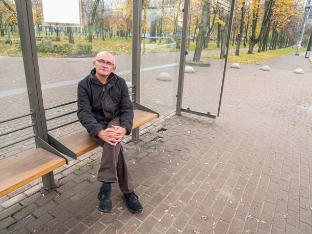 istock Gray-haired man at a public transport stop. 1186653112