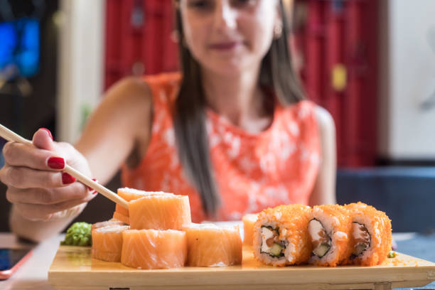 istock Female in cafe eats sushi with chopsticks. Sushi closeup. selective focus 1186654563