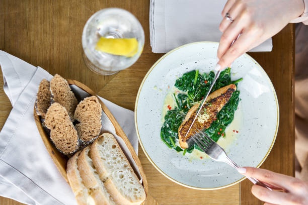 Salmon steak fillet with grainy mustard and spinach. Lunch in a restaurant, a woman eats delicious and healthy food. Restaurant menu, a series of photos of different dishes