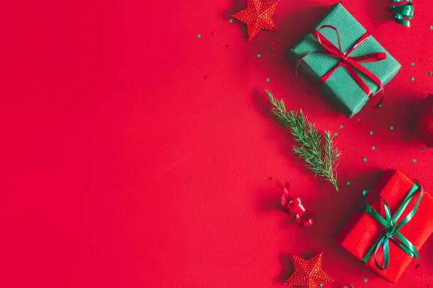 Photo of Christmas composition. Gift box, christmas decorations on red background. Flat lay, top view, copy space