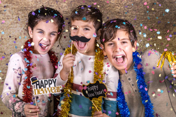 tre bambini felici che festeggiano il capodanno a casa - new year eve foto e immagini stock