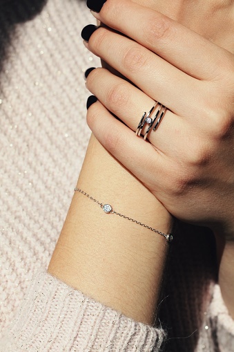 Stars. Tender jewerly for female hands, close up shot. Elegance accessories for look and beauty. Rings on fingers and bracelet in soft light with sweater. Gift for relationship. Fashion, love concept.