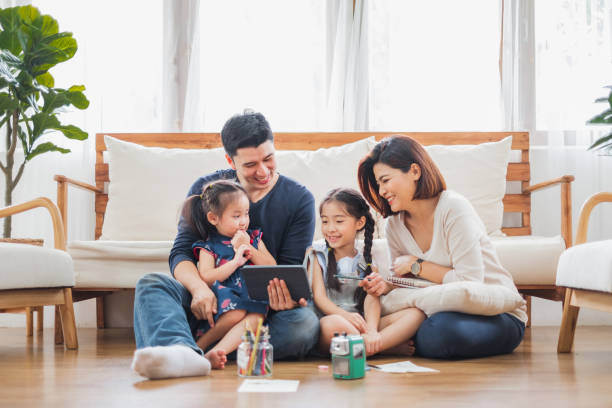 happy asian family using tablet, laptop for playing game watching movies, relaxing at home for lifestyle concept - father digital tablet asian ethnicity daughter imagens e fotografias de stock