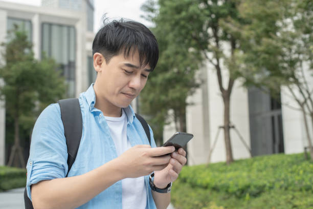istock young asian man using mobile phone with office building 1186673529