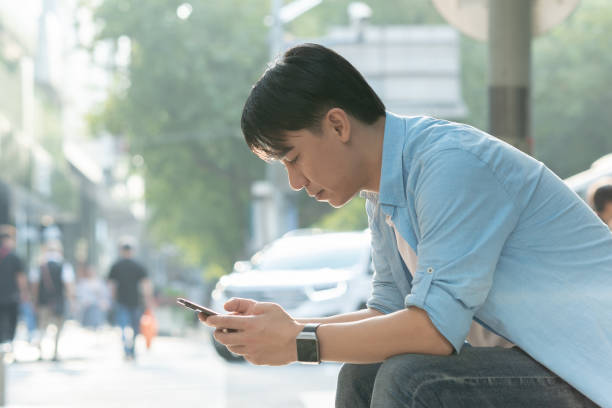 istock young asian man using mobile phone on street 1186674346