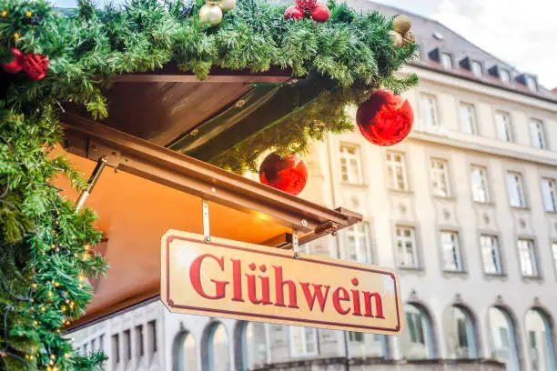 Christmas market in Germany, Europe. Gluhwein Hot Mulled Wine Sign plate at Famous outdoor Marienplatz Christmas Market in Munich on old building background.