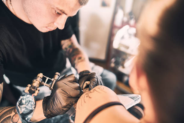 istock Tattoo Artist making a tattoo on a customer's shoulder 1186679453