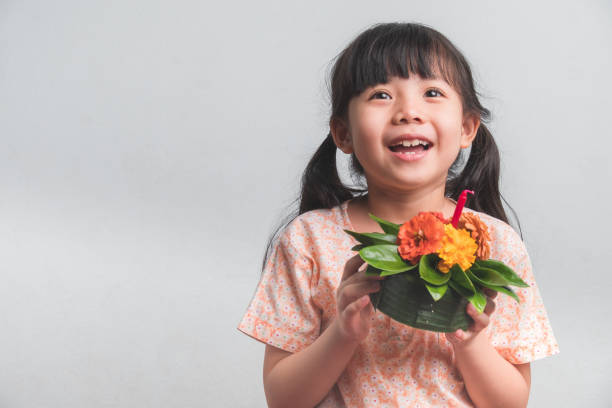 Cute Little Asian Thai Girl with Krathong. Portrait of Little Thai Girl and Krathong In Thai folk costume in orange color. with Space for Text. loi krathong stock pictures, royalty-free photos & images