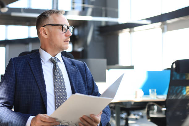 istock Successful mature entrepreneur is studying documents with attentive and concentrated look. 1186687122