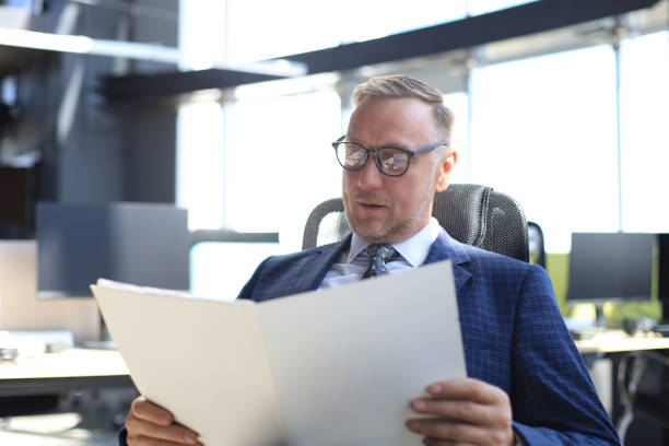 istock Successful mature entrepreneur is studying documents with attentive and concentrated look. 1186687141