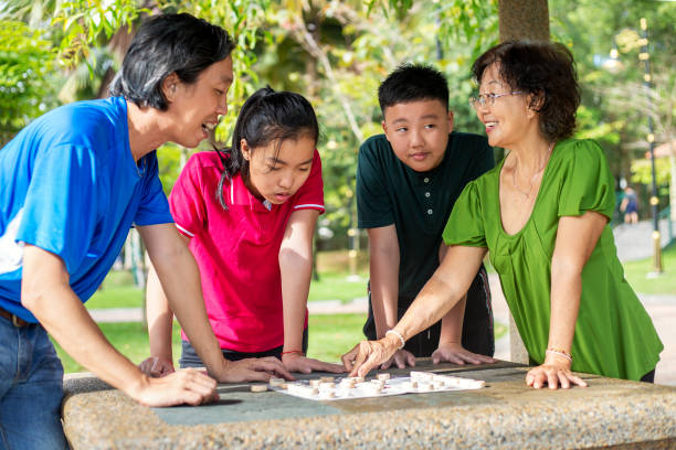 famille multigénérationnelle jouant aux échecs chinois ou xiang qi dans le stationnement public - chinese chess leisure games chinese culture traditional culture photos et images de collection