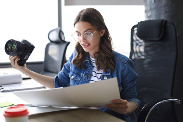 istock Young architect holding digital camera and looking on blueprint while working in the creative office. 1186688201