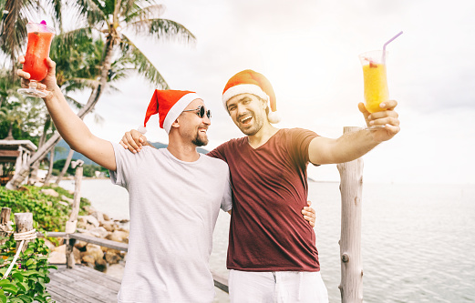 Happy handsome young men, gay family, celebrates New Year and Christmas at a tropical resort, LGBT values, equal rights for everyone