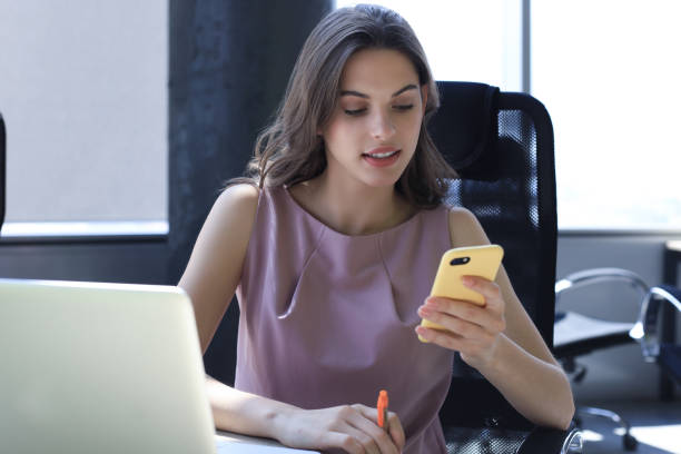 istock Attractive business woman using smart phone while sitting at the office desk. 1186689243