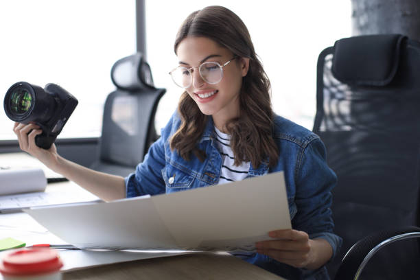 istock Young architect holding digital camera and looking on blueprint while working in the creative office. 1186689664