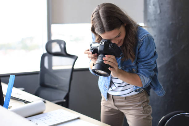 istock Concentrated young designer using digital camera while standing near the desk in her creative office. 1186690264