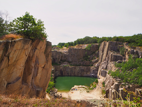 People in a quarry, partly with climbing equipment. Quarry is filled with water.