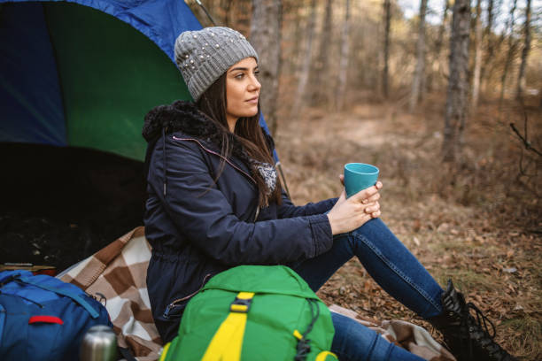 Young woman infront tent drinking hot tea