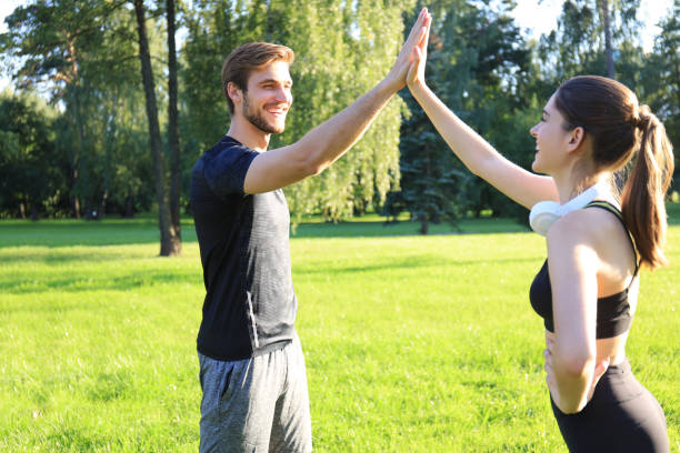 istock Happy young couple giving high five while standing in park. 1186693233
