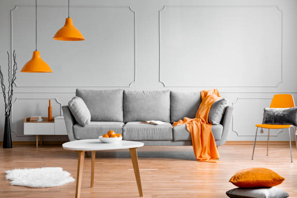 istock Orange lamp above grey scandinavian sofa in modern interior 1186694419