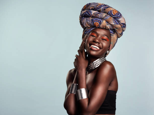 Whatever gets you glowing do that Studio shot of a beautiful young woman wearing a traditional African head wrap against a grey background headdress stock pictures, royalty-free photos & images